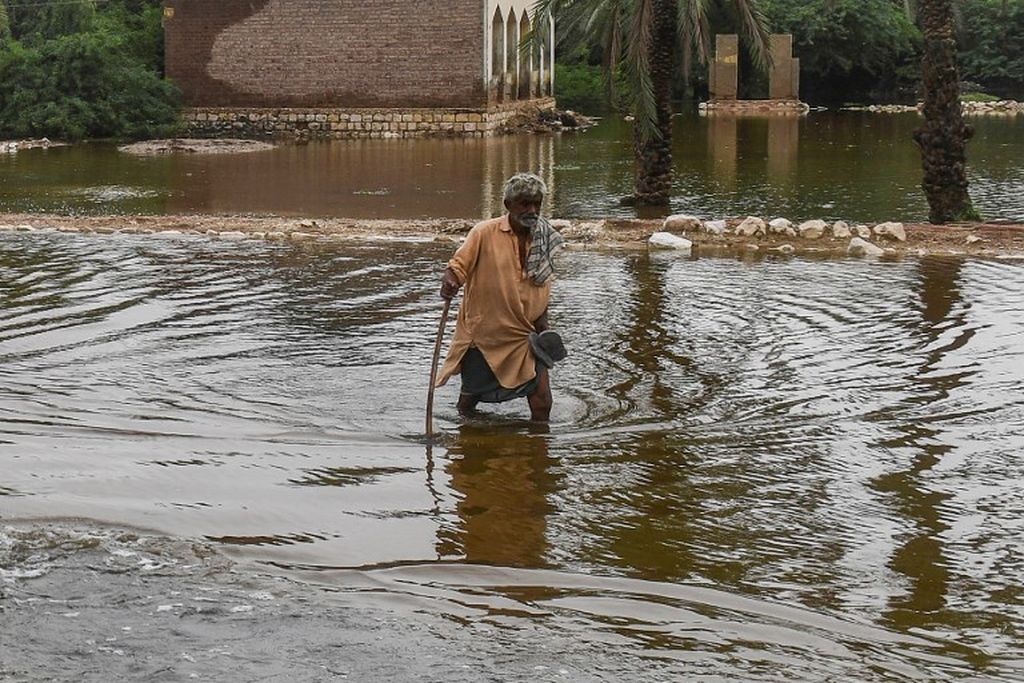 Seorang pria mengarungi banjir setelah hujan monsun di Sukkur, Provinsi Sindh, Pakistan selatan, Jumat (26/8/2022). 