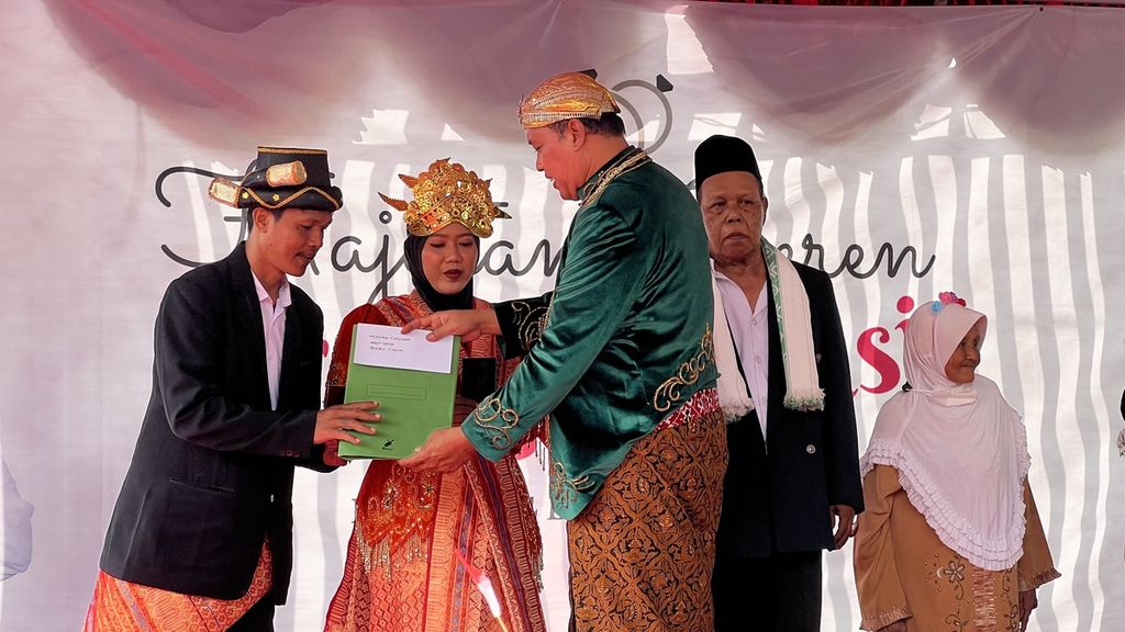 Pelaksana Tugas Wali Kota Bekasi Tri Adhianto menyerahkan buku nikah secara simbolis kepada perwakilan pasangan pengantin isbat nikah di halaman Stadion Patriot Chandrabaga, Kota Bekasi, Jawa Barat, Minggu (4/12/2022).