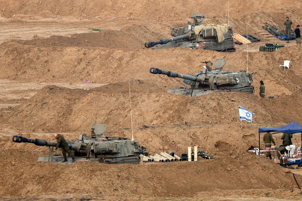 Gambar yang diambil dari Israel selatan di perbatasan dengan Jalur Gaza pada 27 Desember 2023 menunjukkan kendaraan artileri <i>self-propelled </i>Howitzer di tengah pertempuran yang sedang berlangsung antara Israel dan kelompok Hamas.