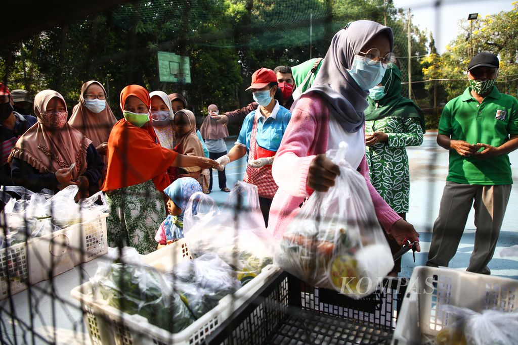 Warga memilih bahan makanan siap masak yang dibagikan bertepatan dengan Hari Kartini di lapangan perumahan Taman Asri, Larangan, Kota Tangerang, Banten, Rabu (21/4/2021). Kegiatan berbagi bahan makanan yang digagas oleh warga bernama Tuti Hernowo ini telah berjalan sejak awal pandemi tahun 2020. Sebanyak 100 paket bahan makanan yang dibagikan seminggu sekali ini berasal dari sumbangan para donatur.