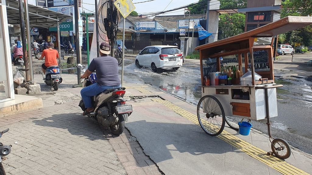 Pemotor melintas di atas trotoar untuk menghindari genangan air di Jalan Ceger Raya, Jurangmangu Timur, Pondok Aren, Tangerang Selatan, Kamis (4/5/2023). 