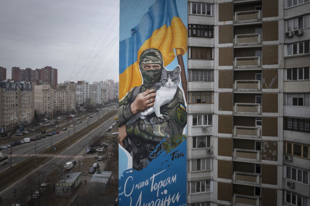 Sebuah mural menampilkan gambar prajurit Oleksiy Movchan memegang kucing yang diselamatkan sebelum kematiannya, di dinding sebuah apartemen di Kyiv, Ukraina, Kamis (1/2/2024). 