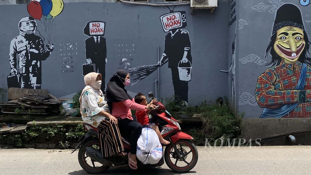 Warga melintasi mural yang dibuat untuk melawan penyebaran informasi palsu (hoaks) di masyarakat di Jalan KH Hasyim Ashari, Kota Tangerang, Banten, Senin (22/2/2021).