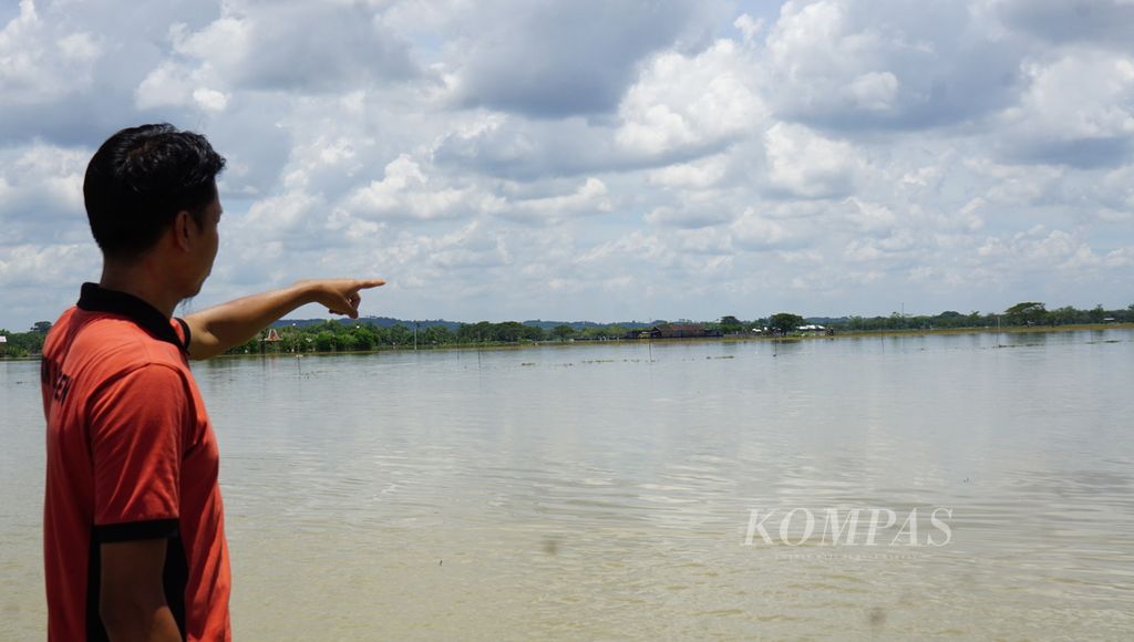 Seorang warga menunjukkan sawah miliknya yang tergenang banjir, di Desa Tangkil, Kecamatan Sragen, Kabupaten Sragen, Jawa Tengah, Jumat (3/3/2023). Banjir merendam wilayah tersebut sejak Rabu (1/3/2023) malam. Genangan air mulai surut meski volumenya belum signifikan.