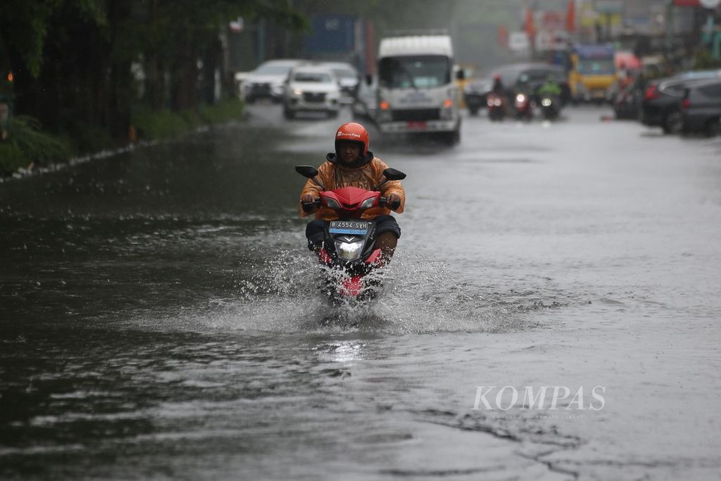 Warga dengan mengendarai motor listrik berusaha melalui genangan banjir di kawasan Kelapa Gading, Jakarta Utara, Jumat (22/3/2024). 