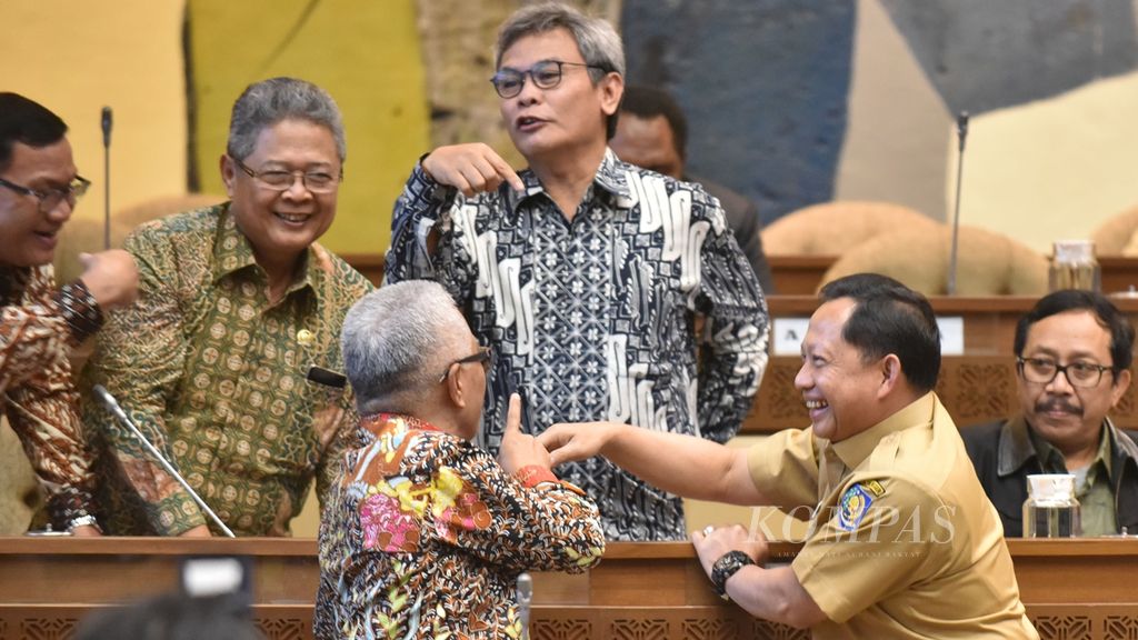 Menteri Dalam Negeri Tito Karnavian bernicang bersama anggota Komisi II DPR RI sebelum memulai rapat bersama dengan Komisi II DPR RI di Kompleks Senayan, Jakarta, Selasa (26/11/2019).