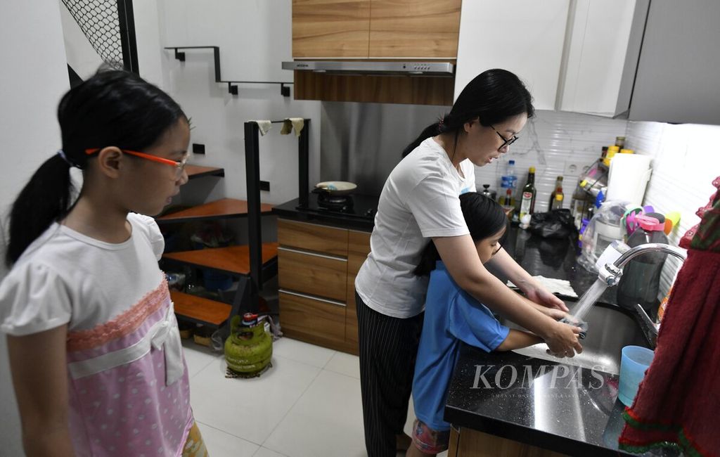 Rina Rahayu (41) membantu putrinya, Ivory Carol, mencuci dan mengeringkan kain lap di rumahnya di Kalideres, Jakarta Barat, Kamis (13/4/2023). 