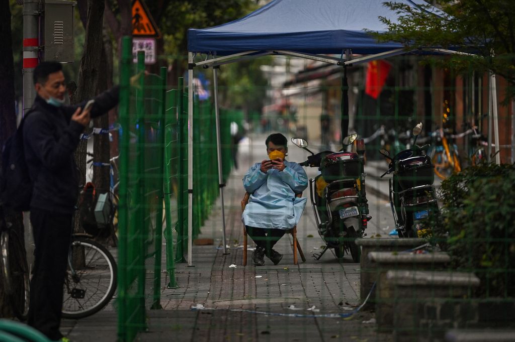 Seorang petugas terlihat berjaga di dalam pagar sebuah area yang dikarantina total (<i>lockdown</i>) di Distrik Changning setelah muncul laporan kasus penularan Covid-19 di Shanghai, China, 8 Oktober 2022. 