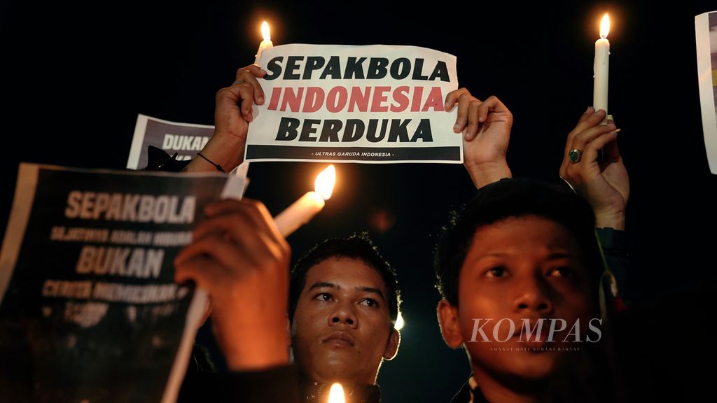 Pencinta sepak bola aksi tabur bunga, menyalakan 1.000 lilin dan doa bersama untk menghormati kawan-kawan Aremania yang menjadi korban Tragedi Kanjuruhan di pintu masuk Asia Afrika, Stadion Gelora Bung Karno, Jakarta, Minggu (2/10/2022) malam. 
