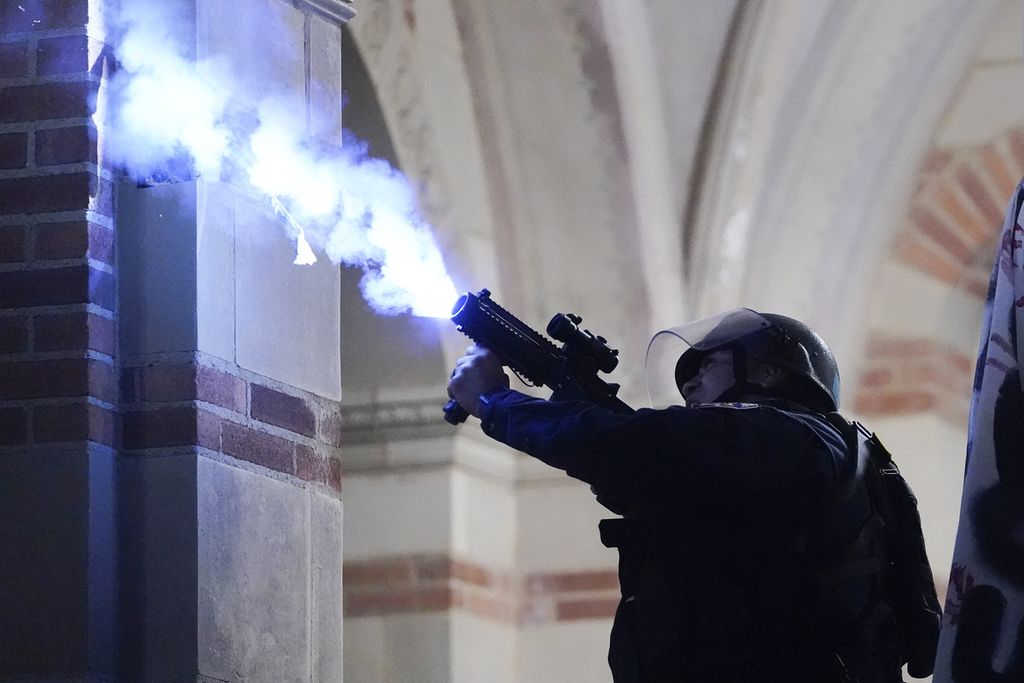 A police officer fires a smoke bomb to disperse pro-Palestinian protesters on the campus of the University of California, Los Angeles (UCLA), in Los Angeles, California, Thursday (2/5/2024).