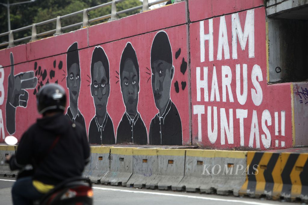Mural berisi tuntutan untuk penuntasan kasus pelanggaran HAM menghiasi Jembatan layang Grogol di depan Kampus Universitas Trisakti, Jakarta, Kamis (28/7/2022). Saat ini Mahkamah Agung meloloskan delapan nama calon hakim <i>ad hoc </i>pelanggaran hak asasi manusia (HAM) berat Paniai, Papua.