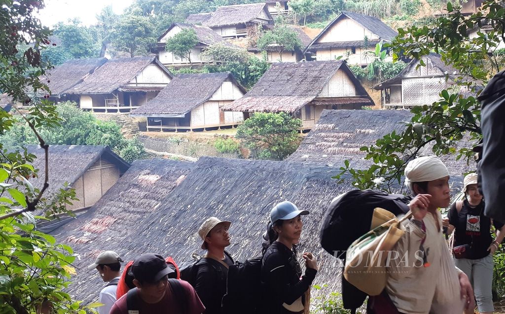 Warga Baduy Dalam (berpakaian putih) berjalan di antara pengunjung yang melewati kawasan Baduy Luar di Desa Kanekes, Kecamatan Leuwidamar, Kabupaten Lebak, Banten, Sabtu (10/2/2024). Warga Baduy Dalam menjalani bulan Kawalu pada 13 Februari hingga 13 Mei 2024.