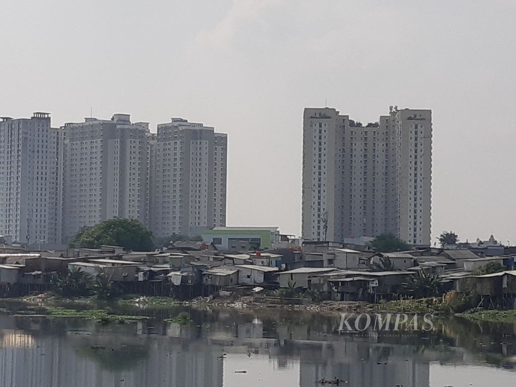 Situasi kawasan kumuh dengan latar belakang gedung tinggi di bantara Waduk Pluit, Jakarta Utara, Rabu (19/6/2024). Kemiskinan dan permukiman kumuh masih menjadi pekerjaan rumah bagi Pemerintah Provinsi DKI Jakarta. Masalah ini dikhawatirkan akan menghalangi visi Jakarta menjadi kota global. 