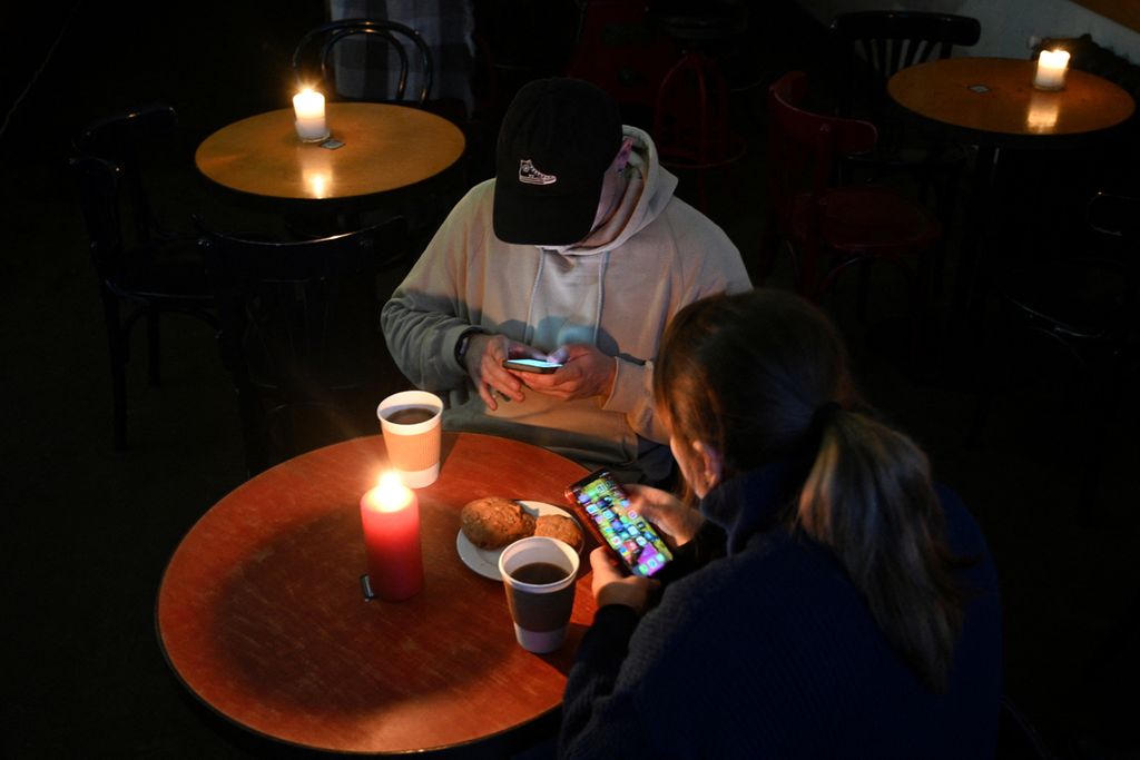 Warga beristirahat di kafe di Lviv, Ukraina barat, saat kota itu mendapat giliran pemadaman listrik pada 24 November 2022, setelah serangan terbaru pasukan Rusia atas infrastruktur energi Ukraina. 