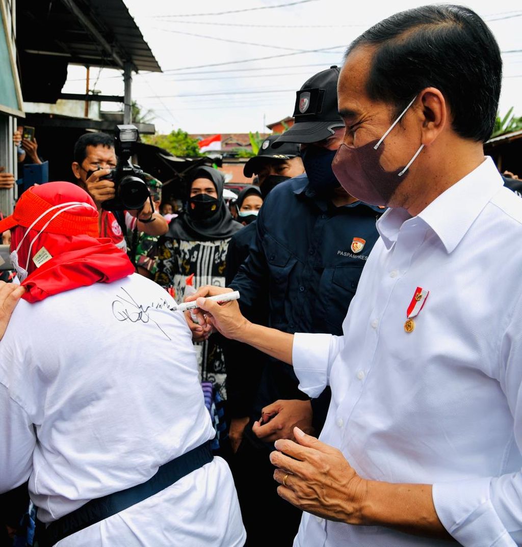 Seorang ibu meminta tanda tangan Presiden Joko Widodo ketika Kepala Negara menyerahkan bantuan langsung tunai bagi pedagang di Pasar Baru Tanjung Enim, Sumatera Selatan, Senin (24/1/2022).