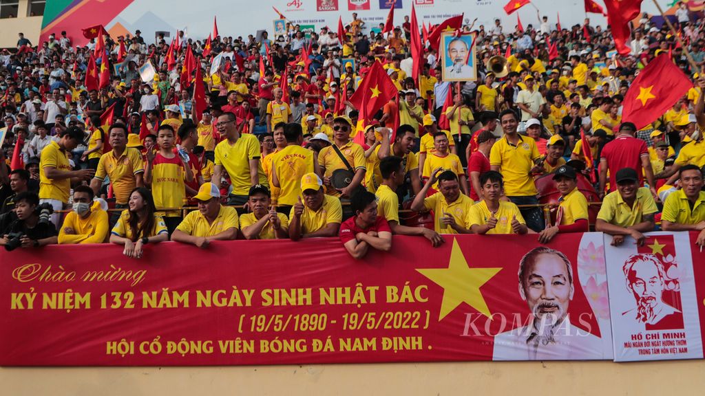 Ratusan warga membawa sejumlah atribut dan spanduk bergambar tokoh Ho Chi Minh di Stadion Thien Truong, Nam Dinh, Vietnam, untuk menyaksikan laga pertandingan sepakbola yang bertepatan dengan perayaan hari kelahiran tokoh tersebut, Kamis (19/5/2022). 