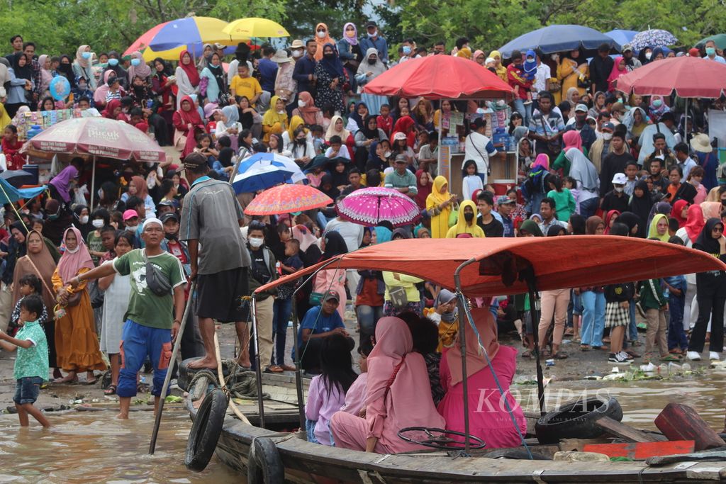 Ratusan warga memadati tepian Sungai Musi, Palembang, Sumatera Selatan, Minggu (21/8/2022). Mereka sedang menunggu final perahu bidar yang merupakan perlombaan yang kerap dilaksanakan pada hari kemerdekaan. 