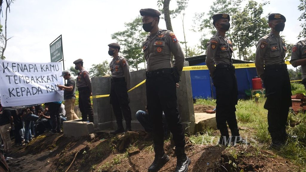 Petugas kepolisian berjaga di depan lokasi otopsi dua korban Tragedi Kanjuruhan, yaitu NDR (16) dan NDB (13), di Tempat Pemakaman Umum (TPU) Dusun Patuk, Desa Sukolilo, Kecamatan Wajak, Kabupaten Malang, Jawa Timur, Sabtu (5/11/2022). 