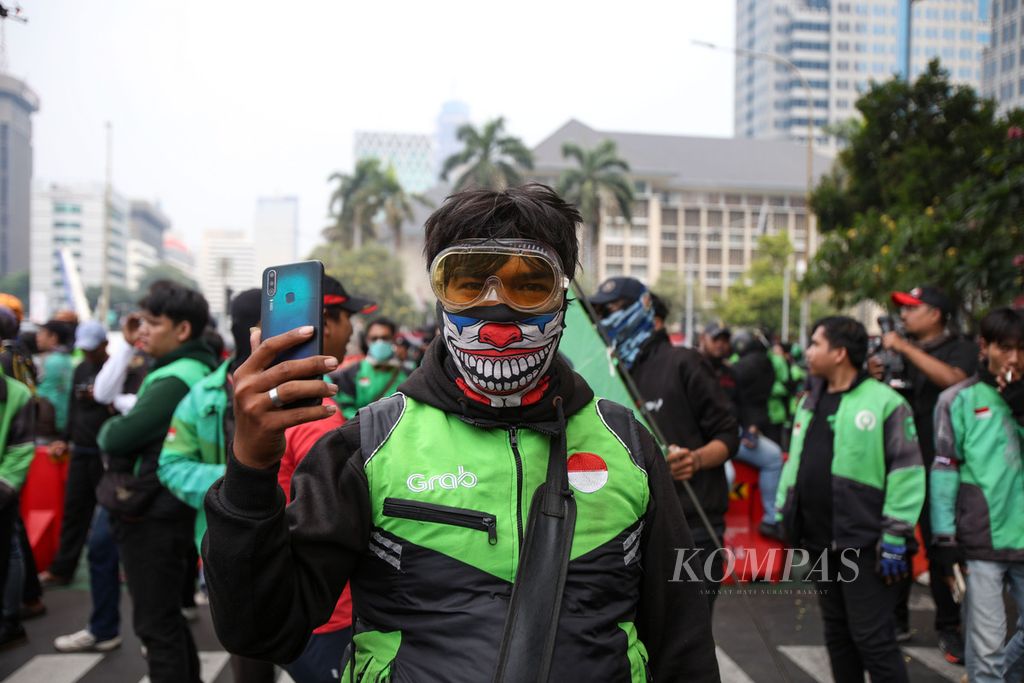 Salah seorang pengemudi ojek <i>online</i> atau ojek daring merekam unjuk rasa di kawasan Patung Kuda Wijaya, Jakarta, Kamis (29/8/2024). 