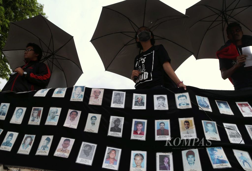 Peserta Aksi Kamisan membawa payung hitam saat mengikuti aksi tersebut yang dilaksanakan di depan Istana Merdeka, Jakarta, Kamis (12/1). Aksi untuk menuntut penuntasan pelanggaran HAM itu sudah dilakukan kelompok tersebut selama 10 tahun.