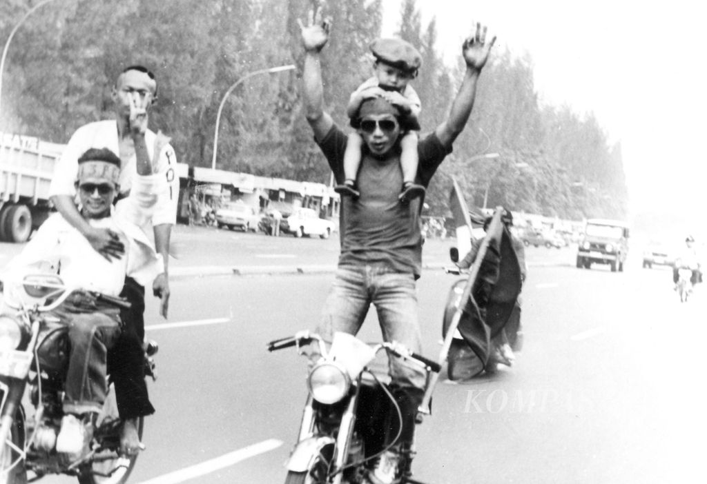Sambil menggendong anak kecil berusia dua atau tiga tahun, pengendara sepeda motor peserta kampanye PDI ini berdiri dan mengangkat kedua tangannya. Melaju dengan kecepatan tinggi di jalan Asia Afrika, Jakarta Pusat, sambil mengacungkan tiga jari, Rabu (28/4/1982). Tindakan sembrono itu mempertaruhkan nyawa anak kecil yang belum mengerti apa-apa. 