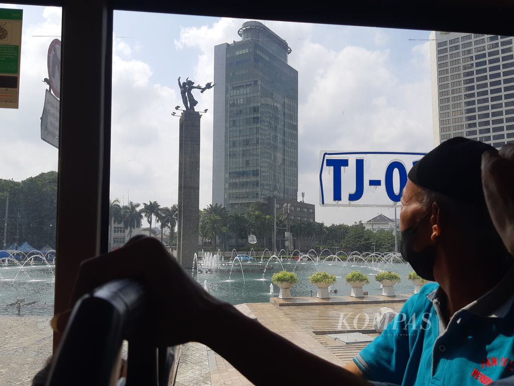Seorang penumpang Bus Wisata Transjakarta sedang melihat monumen selamat datang di kawasan Bundaran Hotel Indonesia, Minggu (14/4/2024). Obyek ini menjadi titik tujuan wisata pada penjelajahan Jakarta. 