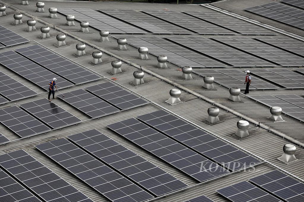 Petugas membersihkan panel pembangkit listrik tenaga surya di atas atap pabrik terigu milik PT Indofood Sukses Makmur Tbk Divisi Bogasari, Cibitung, Bekasi, Jawa Barat, Jumat (9/9/2022). 