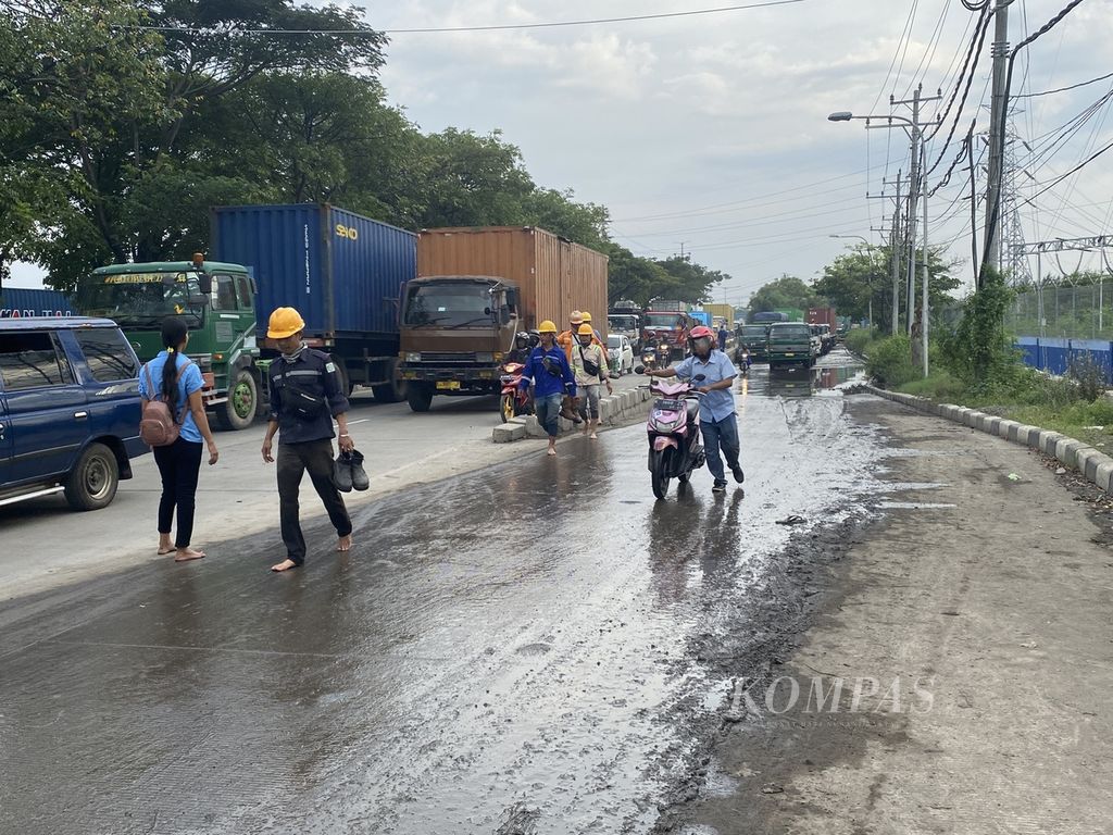 Pekerja di kawasan Lamicitra Pelabuhan Tanjung Emas berjalan kaki sambil menuntun sepeda motor mereka di Jalan Pantura, Kecamatan Semarang Utara, Senin (23/5/2022). 