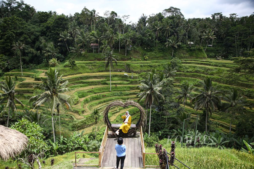 Wisatawan domestik berfoto dengan latar belakang area persawahan di Tegalalang, Kabupaten Gianyar, Bali, Minggu (21/11/2021).  
