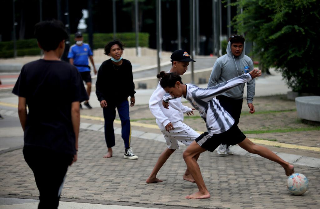 Sejumlah remaja bermain bola di luar area <i>ring road</i> Stadion Gelora Bung Karno, Jakarta Selatan, yang tutup untuk sementara, Minggu (17/1/2021). 