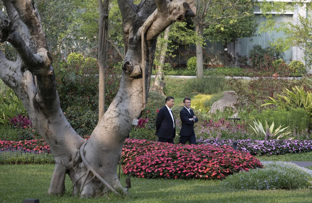 Presiden China Xi Jinping berjalan dengan Presiden Perancis Emmanuel Macron di taman rumah dinas Gubernur Guandong di Guangzhou, China, 7 April 2023.