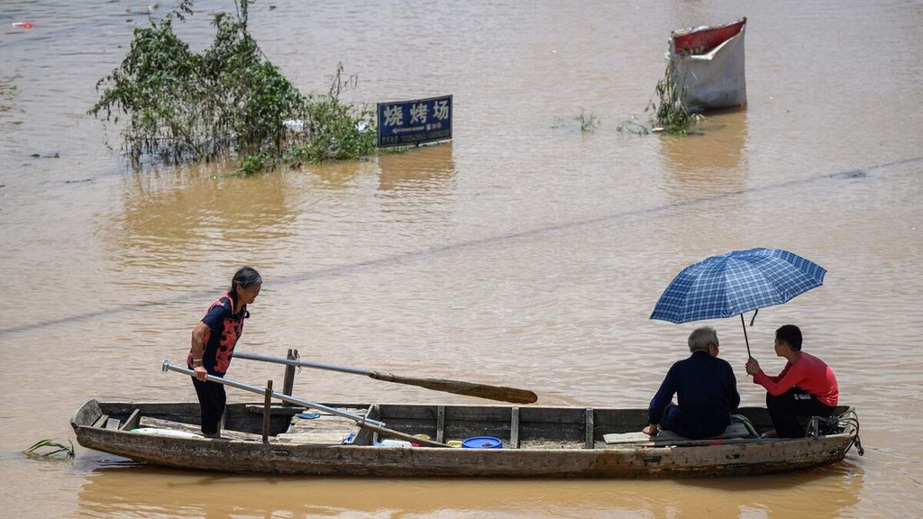 Warga menggunakan perahu untuk melintasi kawasan banjir di Yingde, kota Qingyuan, Provinsi Guangdong, China, 23 Juni 2023. Banjir terjadi setelah China diterjang curah hujan tertinggi selama beberapa hari. 