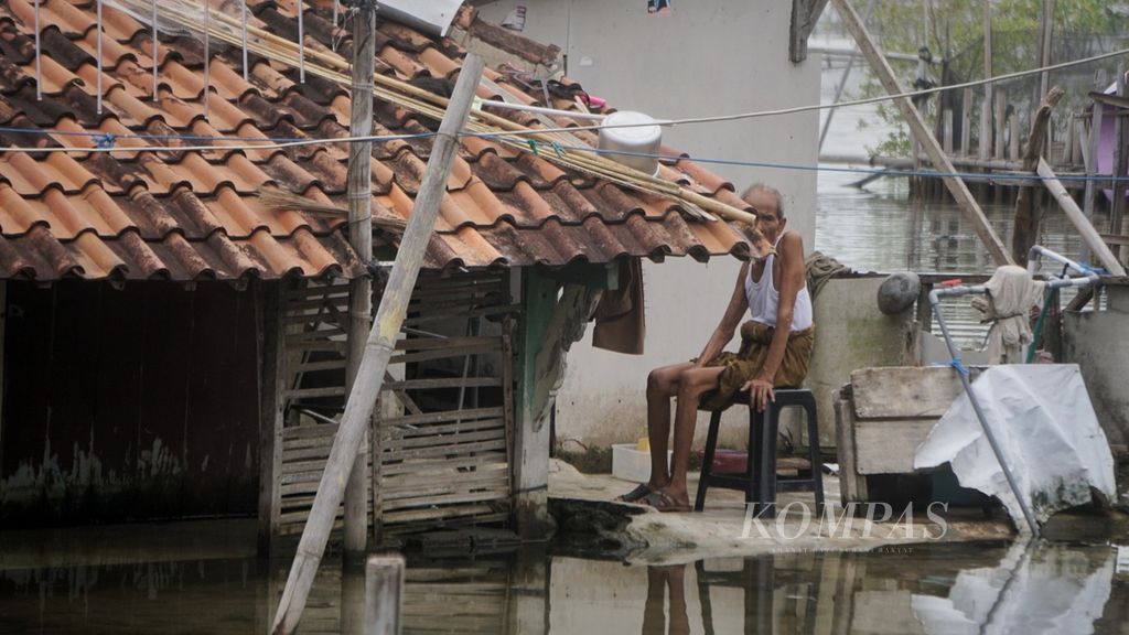 Seorang warga di Desa Timbulsloko, Demak, Jawa Tengah, Selasa (9/5/2023), terlihat masih menempati rumah yang telah terendam air rob.
