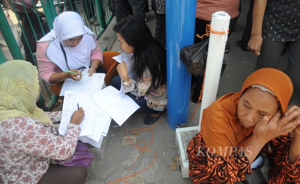 Warga menyiapkan administrasi sebelum mengantre saat mendaftar untuk mengikuti program Jaminan Kesehatan Nasional yang dikelola Badan Penyelenggara Jaminan Sosial Kesehatan, di Sidoarjo, Jawa Timur, pertengahan September 2014. 