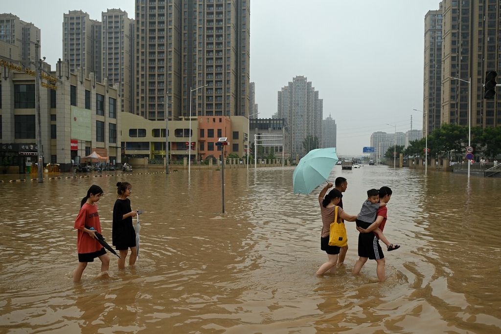 Warga melewati jalanan yang tergenang banjir di pusat kota Zhengzhou, Henan, China, Jumat (23/7/2021). Aktivitas warga terganggu karena banjir ini. Sedikitnya 33 orang tewas dalam bencana tersebut. 