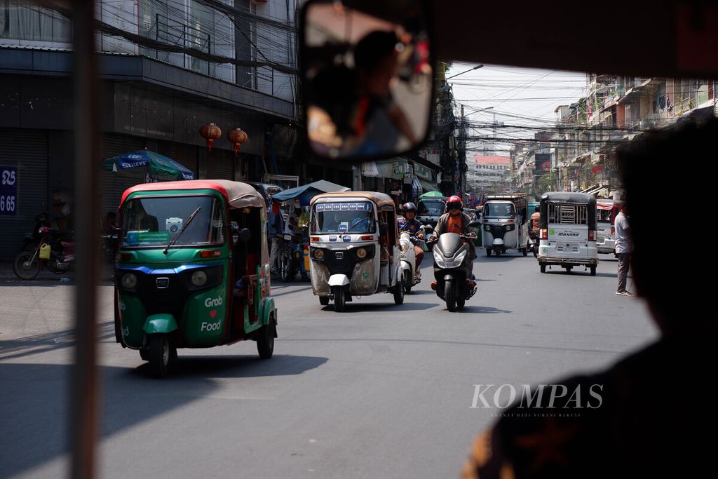 Tuktuk berjalan di kawasan padat permukiman Kota Phnom Penh, Kamboja, Selasa (2/5/2023) siang. Ada dua jenis tuktuk<i></i>di Kamboja, yaitu pertama yang menyerupai bajai di Indonesia dan kedua berupa sepeda motor yang dimodifikasi dengan menambahkan pedati di bagian belakangnya
