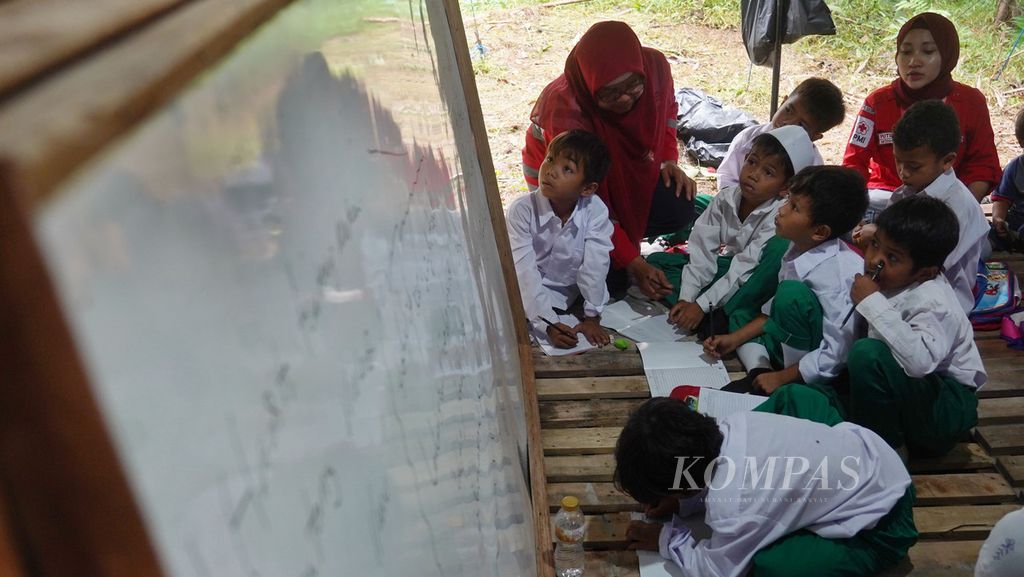 Para siswa Madarasah Ibtidaiyah Mathla'ul Anwar mencatat pelajaran saat mengikuti kegiatan belajar di tenda sekolah darurat di pengungsian Kampung Seupang, Desa Pajagan, Kecamatan Sajira, Lebak, Banten, 27 Januari 2020. Bangunan sekolah di kampung mereka ini hancur diterjang banjir bandang.