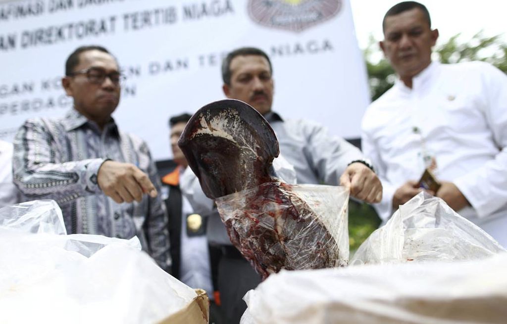Petugas memperlihatkan daging kadaluarsa hasil temuan Tim Pengawasan dan Tertib Niaga Kementerian Perdagangan dimusnahkan dengan cara dibakar di Jakarta, Kamis (28/9). Sebanyak 21,3 ton gula kristal rafinasi yang merembes ke pasar dan 47,9 ton daging beku kadaluarsa dimusnahkan.