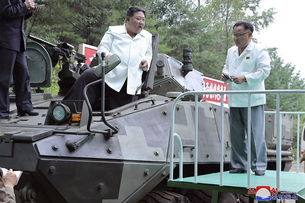 Pemimpin Korea Utara Kim Jong Un (tengah) menaiki kendaraan lapis baja dalam kunjungan sebuah pabrik militer di Korea Utara, 11-12 Agustus 2023. 