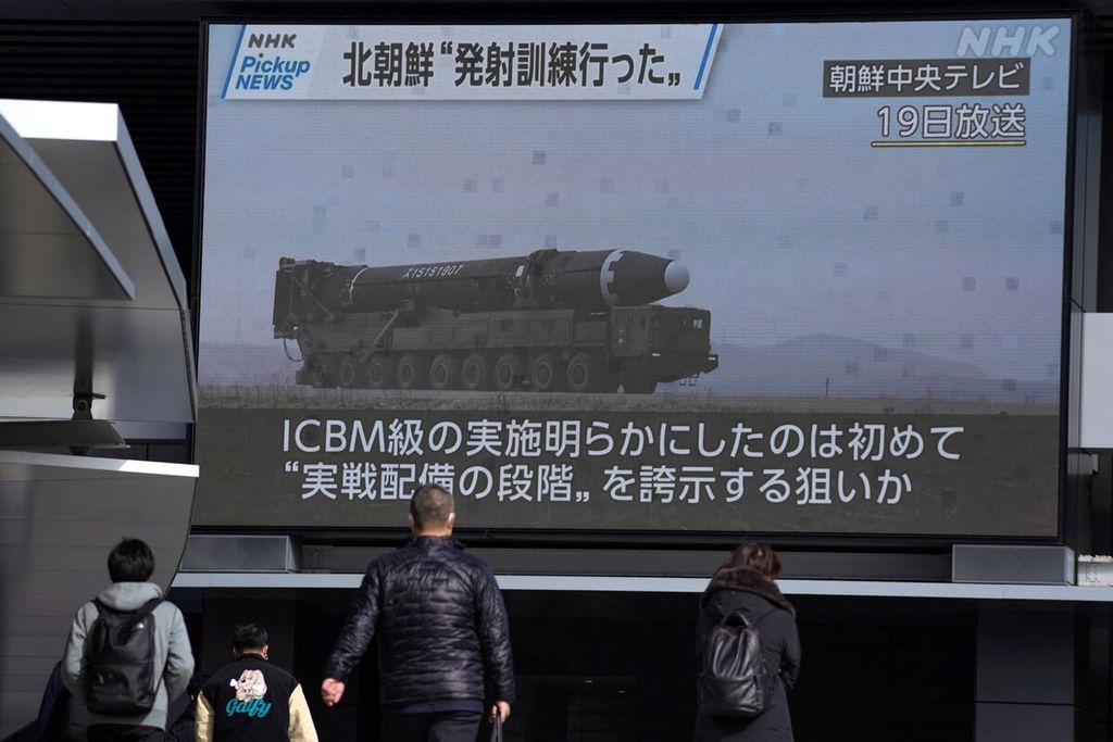 Para pejalan kaki sedang melewati layar yang menunjukkan rekaman peluncuran rudal Korea Utara yang disiarkan oleh Korean Central Television pada 19 Februari 2023. 