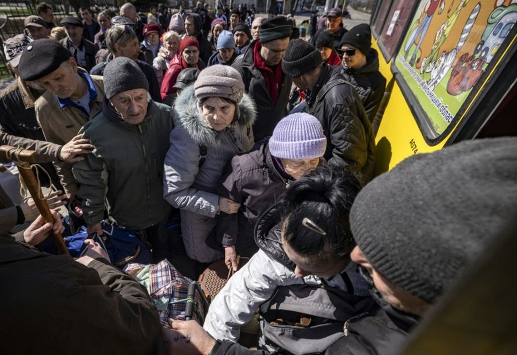 Orang-orang menunggu sebuah bus yang akan mengantar mereka ke stasiun kereta api di Sievierodonestk atau Severodonetsk di Luhansk, Donbas, Ukraina  timur 27 April  2022, saat mereka meningalkan kota itu untuk mengungsi dari serangan Rusia.