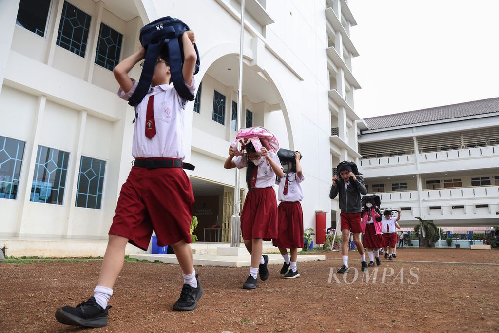 Para siswa sekolah dasar berjalan tertib menuju halaman sekolah saat mengikuti simulasi menghadapi gempa di Kecamatan Pulo Gadung, Jakarta Timur, Rabu (6/12/2023).