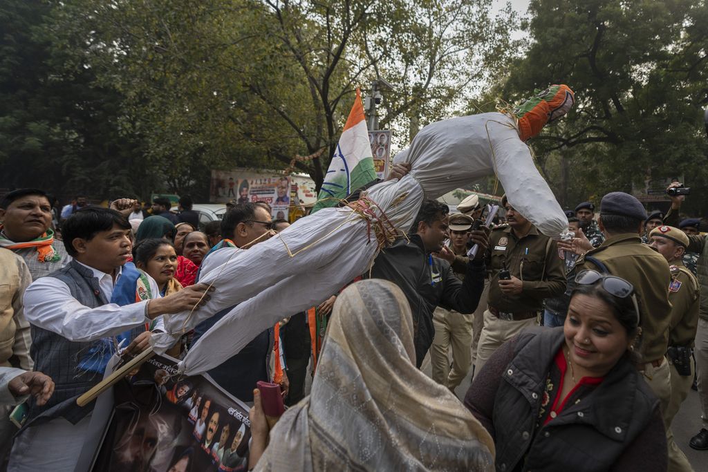 Seorang polisi (kiri) mengambil patung Perdana Menteri India Narendra Modi dari pengunjuk rasa saat unjuk rasa para pemimpin aliansi oposisi INDIA menentang penangguhan lebih dari 140 anggota parlemen dari parlemen, di New Delhi, India, pada 22 Desember 2023. 