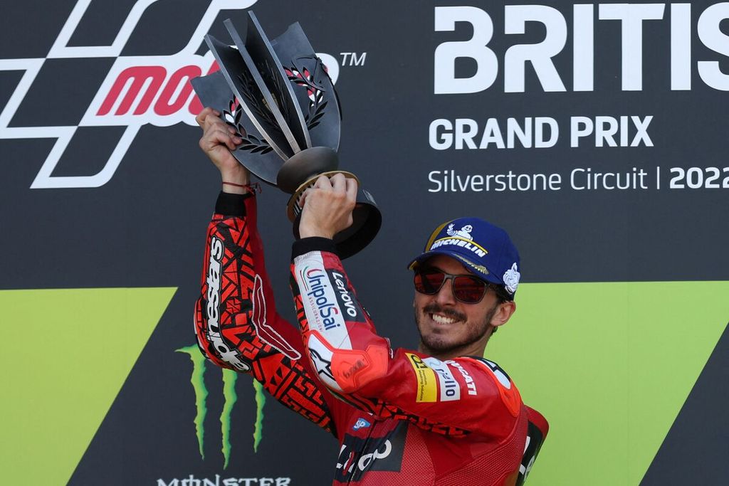 Pebalap tim Ducati, Francesco Bagnaia, melakukan selebrasi dengan mengangkat trofi di atas podium setelah memenangi balapan MotoGP seri Inggris di Sirkuit Silverstone, Inggris, Minggu (7/8/2022). 