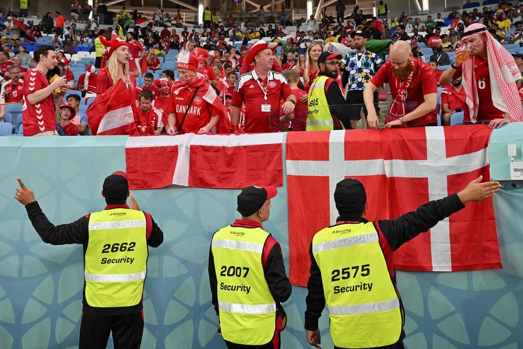 Tiga petugas kemanan Piala Dunia Qatar 2022 mengarahkan suporter Denmark untuk memindahkan bendera Denmark yang dipasang di tribune sebelum laga Grup D antara Australia dan Denmark di Stadion Al-Janoub, Al-Wakrah, Qatar, 30 November 2022. 