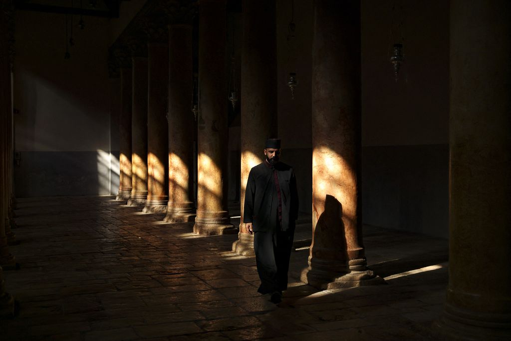 A priest walked along the rows of pillars in a church in Bethlehem, West Bank, ahead of this year's subdued Christmas celebration, on Saturday (2/12/2023).