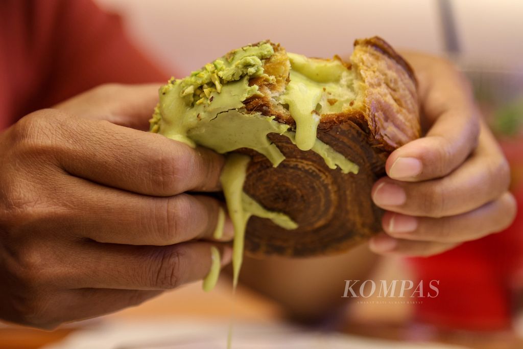 Konsumen memegang cromboloni pesanannya di OUI! Croissant Bar, Pantai Indah Kapuk, Jakarta Utara, Selasa (12/12/2023). 