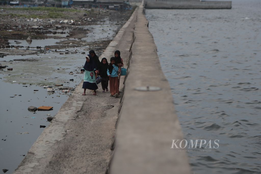 Anak-anak berjalan di samping tanggul laut raksasa di Muara Baru, Jakarta Utara, Rabu (21/6/2023). Tanggul laut raksasa menjadi salah satu upaya pemerintah untuk meredam banjir rob yang kerap terjadi di Jakarta Utara. Banjir rob di Jakarta semakin parah akibat penurunan tanah.