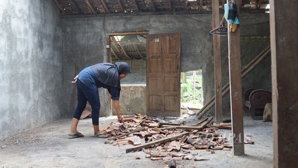Seorang warga merapikan puing-puing genteng yang rontok ke dalam rumahnya, di Desa Pacarejo, Kecamatan Semanu, Kabupaten Gunungkidul, Daerah Istimewa Yogyakarta, Sabtu (1/7/2023). 