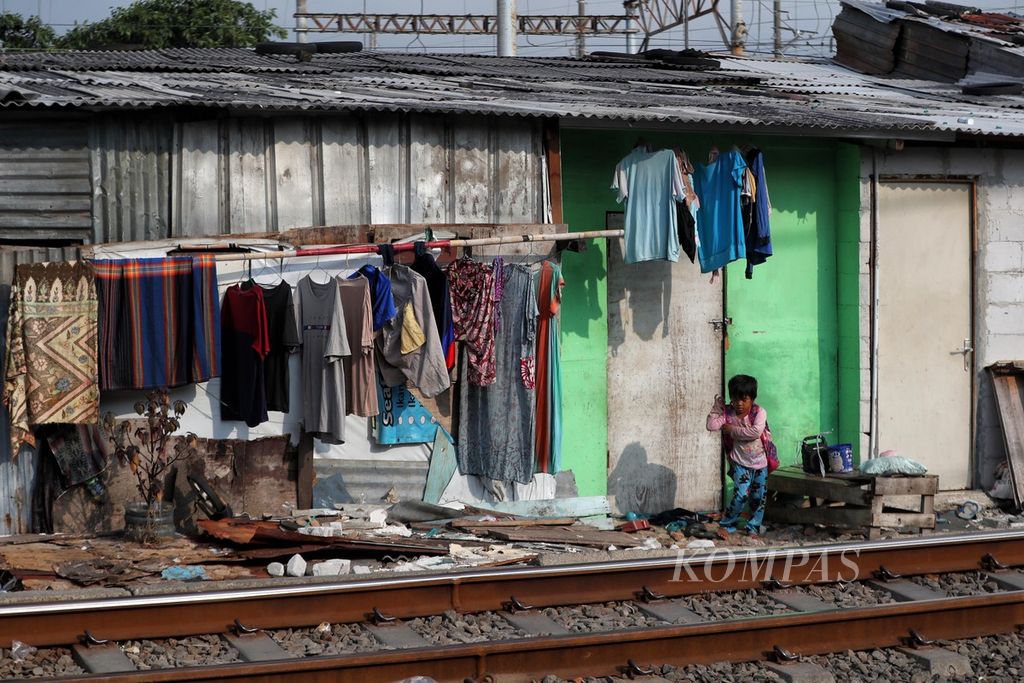 Seorang anak bermain di depan rumah semi permanennya yang berada di tepi jalur kereta di kawasan hunian padat penduduk di Pademangan, Jakarta Utara, jumat (18/6/2021). Kemiskinan memaksa anak-anak tersebut tumbuh dan bermain di tempat yang tak layak. 